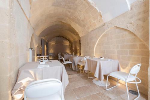 un ristorante con tavoli e sedie bianchi in un edificio in pietra di Aquatio Cave Luxury Hotel & SPA a Matera
