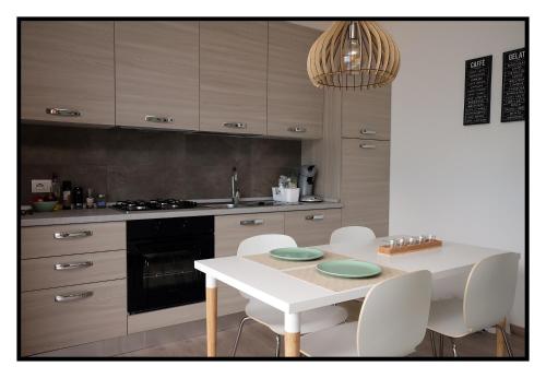 een keuken met een witte tafel en witte stoelen bij Riflessi di Lago in Dorio