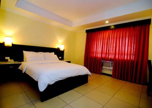 a bedroom with a bed and a red curtain at MO2 Westown Hotel - Mandalagan in Bacolod