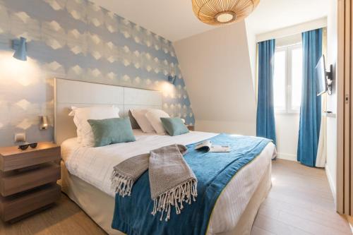 ドーヴィルにあるRésidence Pierre & Vacances Premium Presqu'Ile de la Touquesのベッドルーム1室(ブルーアクセントの壁の大型ベッド1台付)