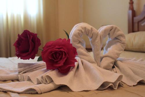 a group of towels on a bed with two roses at Hostal Carlos I in Herrera del Duque
