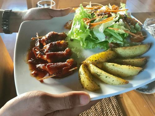 a plate of food with meat potatoes and a salad at Clove Tree Hill in Blimbing