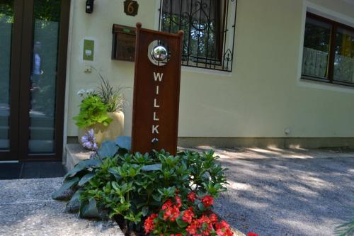 a welcome sign in front of a building with flowers at Gästehaus Pfisterer in Bad Schallerbach