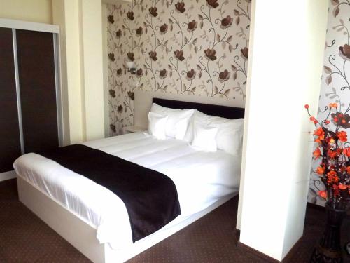 a bedroom with a white bed with a black blanket at West Plaza Hotel in Bucharest