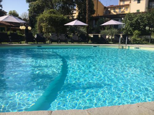 a pool of blue water with chairs and umbrellas at Villa Royal in Florence