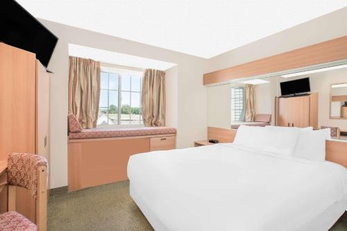 a hotel room with a white bed and a desk at Microtel Inn & Suites by Wyndham Colfax in Colfax