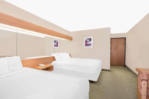 a hotel room with two beds and a chair at Microtel Inn & Suites by Wyndham Colfax in Colfax