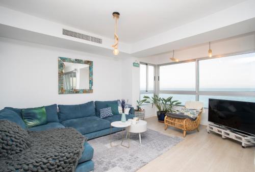Una sala de estar con un sofá azul y un televisor. en Alicante Ocean View, en Alicante