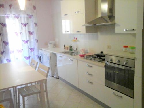 a kitchen with white cabinets and a table and a stove at Casa Poeta in Trapani