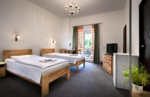 um quarto com 2 camas, uma televisão e um lustre em Penzión Centrál em Zvolen