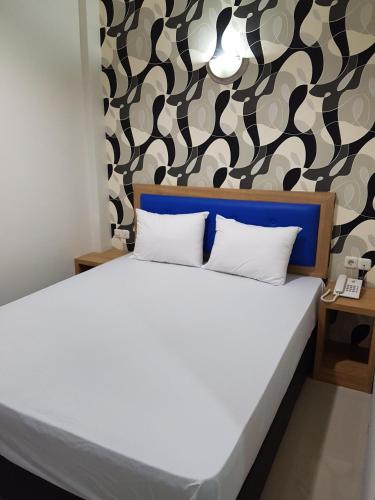 a bedroom with a white bed with a patterned wall at Ethan Hotel Kelapa Gading in Jakarta