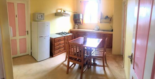 a kitchen with a table and a white refrigerator at Le Rosier in Trou dʼ Eau Douce