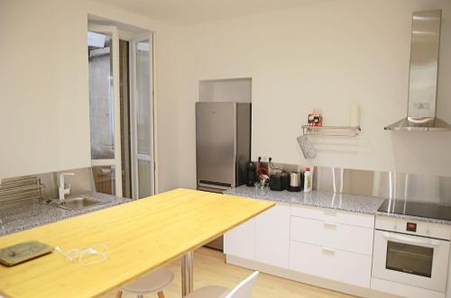 cocina con armarios blancos y mesa de madera en F3 - Standing Centre Ville Calme Et Climatise en Ajaccio