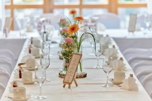a long table with glasses and flowers on it at Posthotel Walhalla Regensburg Ost in Donaustauf