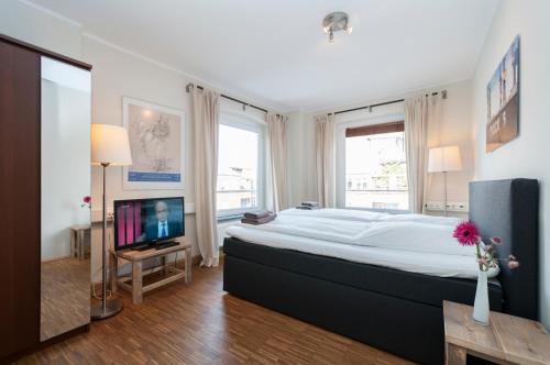 a bedroom with a large bed and a flat screen tv at Appartements an der Elbphilharmonie contactless Check in in Hamburg