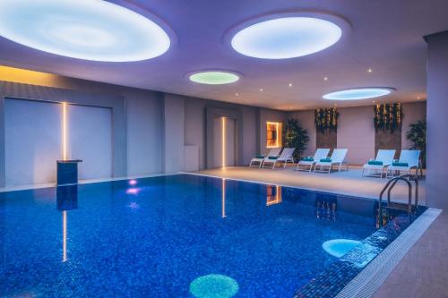 a swimming pool in a hotel with chairs and lights at Heritage Grand Perast By Rixos in Perast