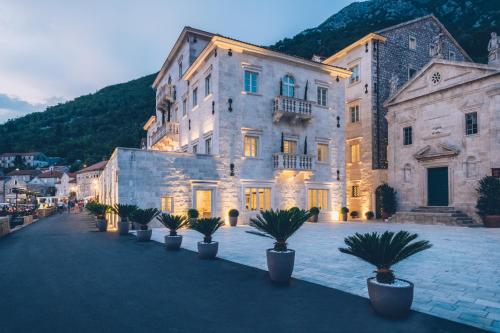 a large building with potted plants in front of it at Heritage Grand Perast By Rixos in Perast