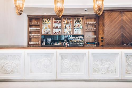a bar with white cabinets and chandeliers at Heritage Grand Perast By Rixos in Perast