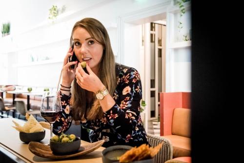 a woman sitting at a table talking on a cell phone at Fitz Roy Urban Hotel, Bar and Garden in Maastricht