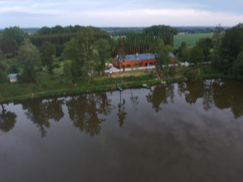 a view of a lake with a house in the background at Florennes Gîte neuf 150 M2 devant un grand lac privé de 2 hectares poissonneux au milieu des bois in Florennes