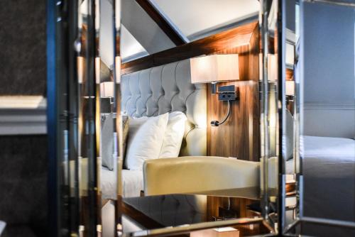 1 dormitorio con cama, silla y espejo en Dalziel Park Hotel, en Motherwell