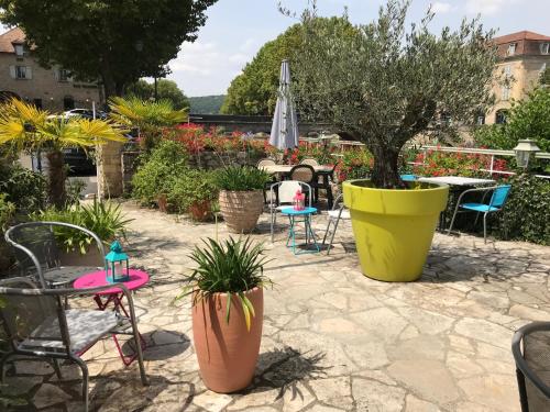 a patio with chairs and tables and plants at Hôtel des Bains in Figeac