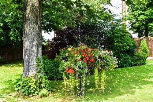a hanging basket of flowers in a yard next to a tree at Dalziel Park Hotel in Motherwell