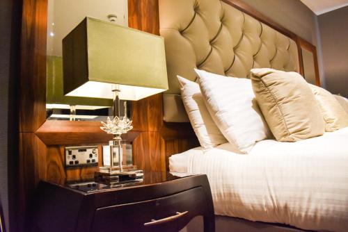 a bedroom with a bed and a lamp on a table at Dalziel Park Hotel in Motherwell