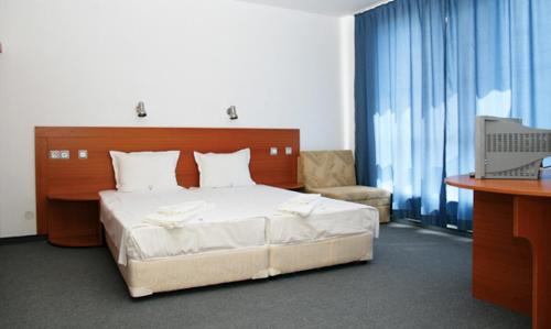 a bedroom with a bed and a desk and a television at Hotel Veleka in Chernomorets