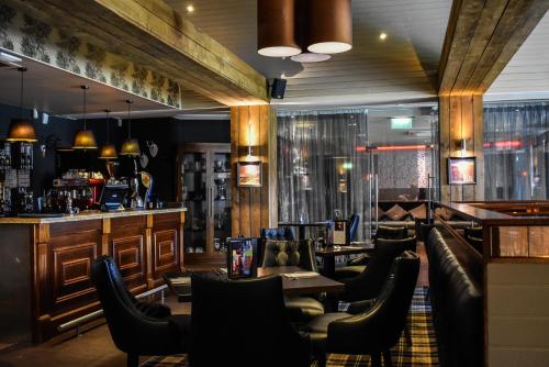 a restaurant with tables and chairs and a bar at Dalziel Park Hotel in Motherwell