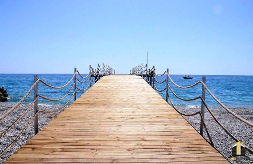 a wooden boardwalk leading into the ocean on a beach at panaroma villaları in Alanya