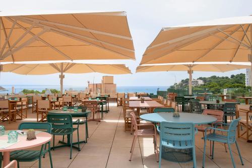 a patio with tables and chairs and umbrellas at INNSiDE by Meliá Calviá Beach in Magaluf