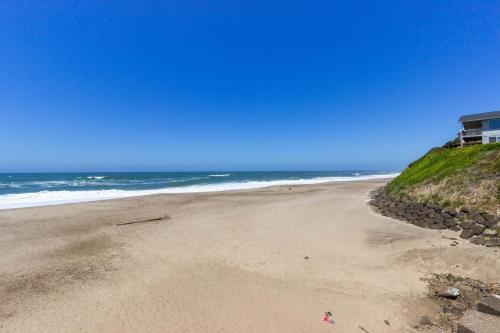 an empty beach with a house and the ocean at Bright Beach Town Bungalow in Gleneden Beach