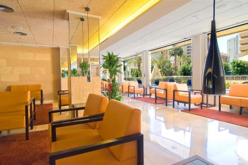 
a living room filled with tables and chairs at Hotel Servigroup Orange in Benidorm
