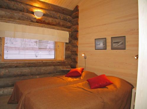 Schlafzimmer mit einem Bett mit roten Kissen und einem Fenster in der Unterkunft Kelokoto Chalets in Ruka