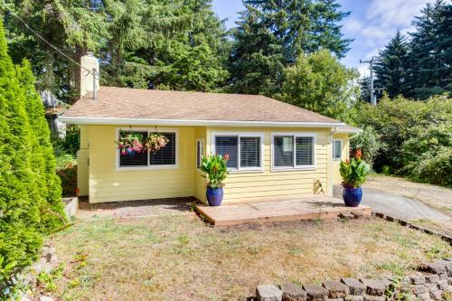 a small yellow house with two potted plants in a yard at Bright Beach Town Bungalow in Gleneden Beach
