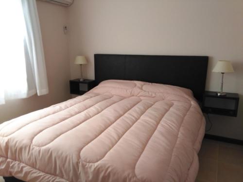 1 cama rosa grande en un dormitorio con 2 lámparas en Apartamentos Valeria en Valeria del Mar