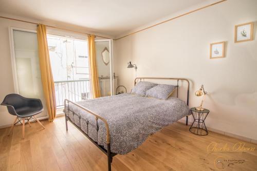 a bedroom with a bed and a chair and a window at Chez Emy in Sète