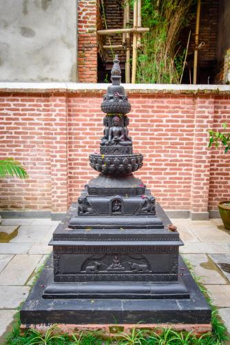 a black pagoda sitting in the middle of a garden at Hotel Timila in Pātan