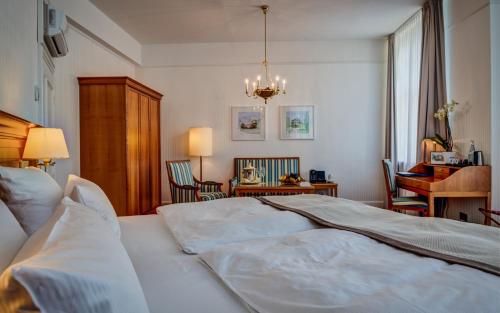 a bedroom with a large white bed and a desk at Schlosshotel Karlsruhe in Karlsruhe
