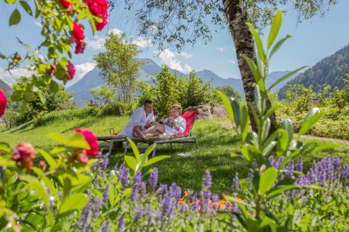 a man and a woman sitting on a bench in a garden at Gesundhotel Bad Reuthe in Vorderreuthe