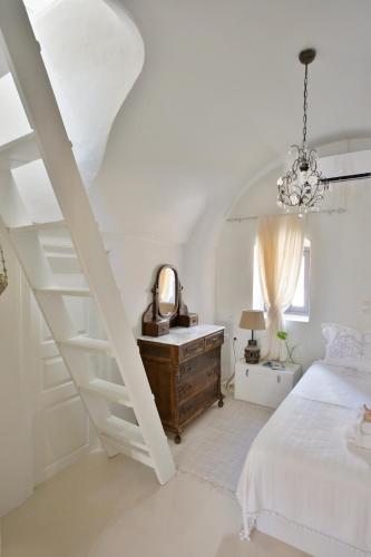 a white bedroom with a bed and a staircase at ALIA MANSION by K&K in Megalokhori