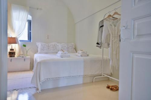 a white bedroom with a bed and a dress rack at ALIA MANSION by K&K in Megalokhori