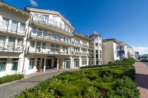 a large white building with balconies on a street at Dorint Strandhotel Binz/Rügen in Binz