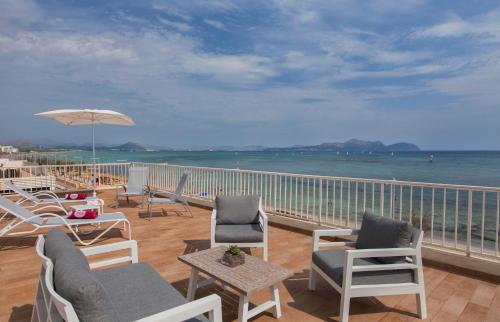 a deck with chairs and an umbrella and the ocean at JS Miramar in Can Picafort