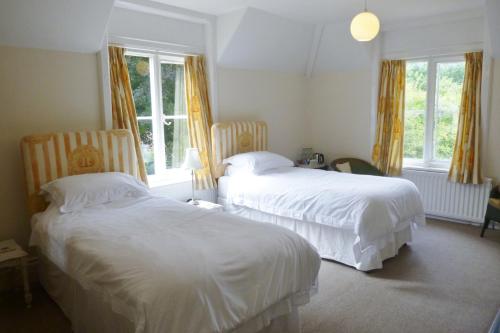 a hotel room with two beds and two windows at Bijou B&B Lulworth in Lulworth Cove