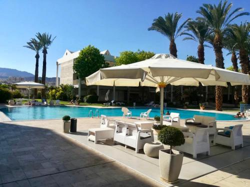 エイラットにあるEsterin Royal Park Apartments Eilatのテーブルと椅子、パラソル付きのプールを提供しています。