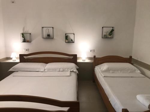 two beds in a room with two lamps on the wall at Vila Alikaj in Sarandë