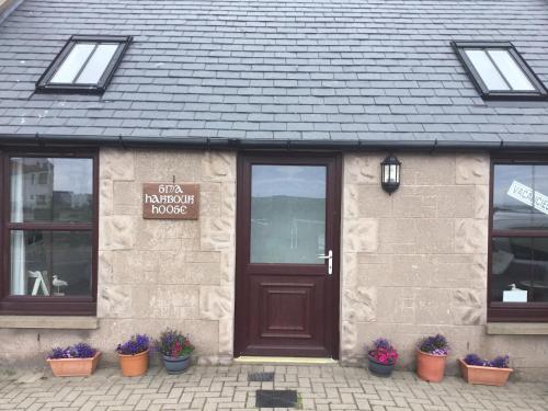 a building with a brown door and some potted plants at Sma Harbour Hoose in Gourdon
