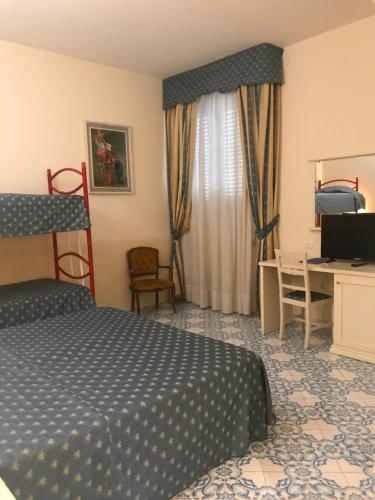 a bedroom with a bed and a desk with a computer at Hotel Alexander Palme in Chianciano Terme